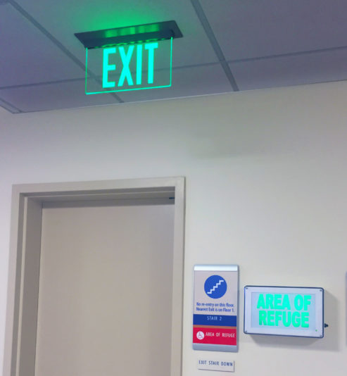 The ELT Elite Edge-Lit Exit Sign is seen here in a hallway outside of a stairwell for public safety.