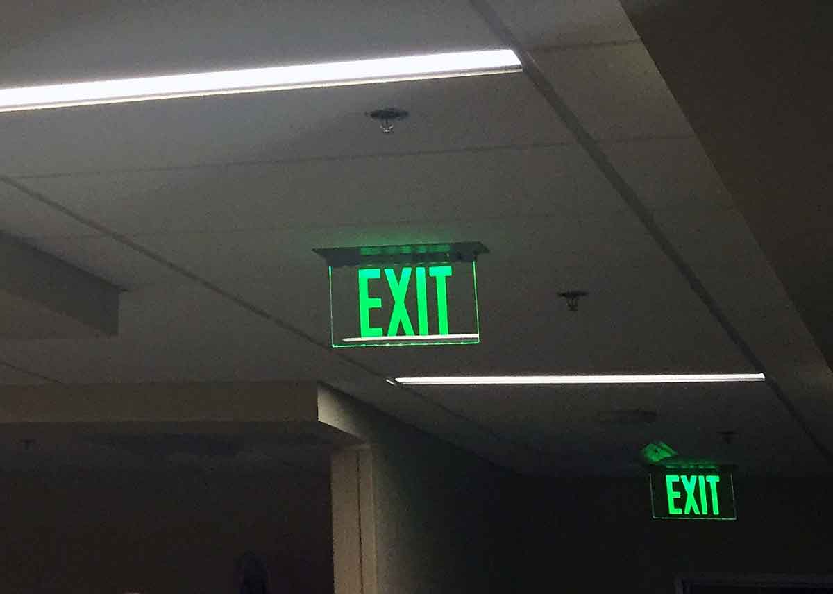 The ELT Elite Edge-Lit Exit Sign is seen here in a dimly lit hallway directing the way to safety.