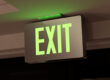 A photo of a green exit sign glowing after dark
